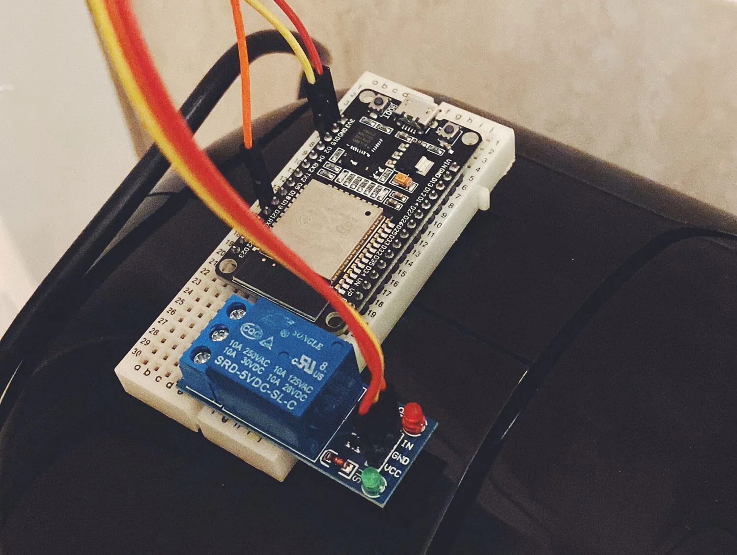 ESP32 and relay on a breadboard sitting on top of a coffee machine