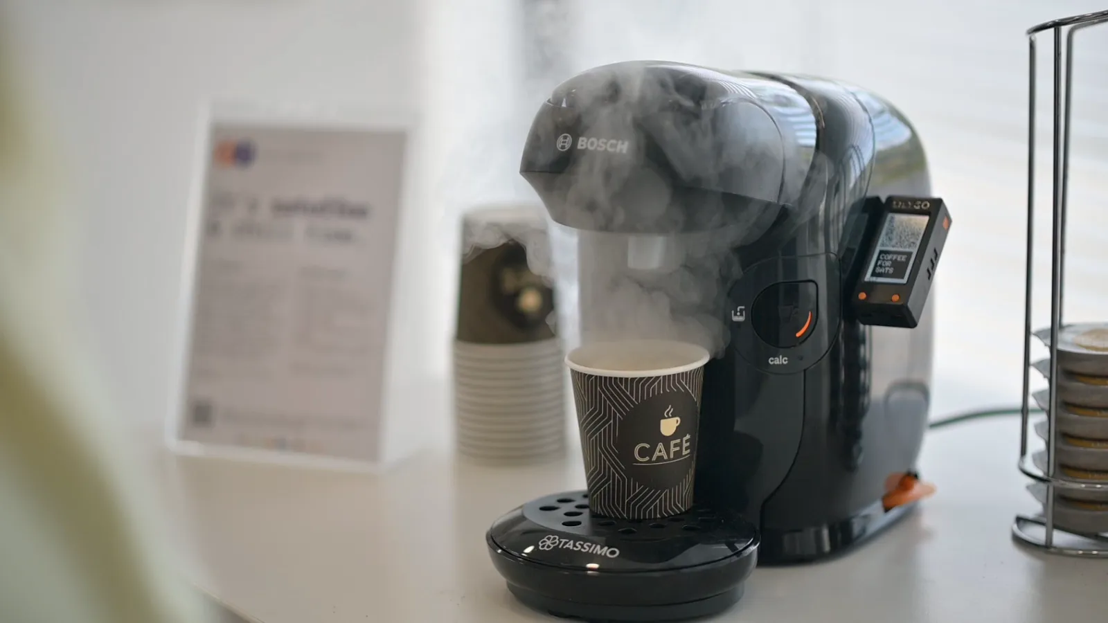 A freshly brewed coffee steaming next to the Satoffee screen